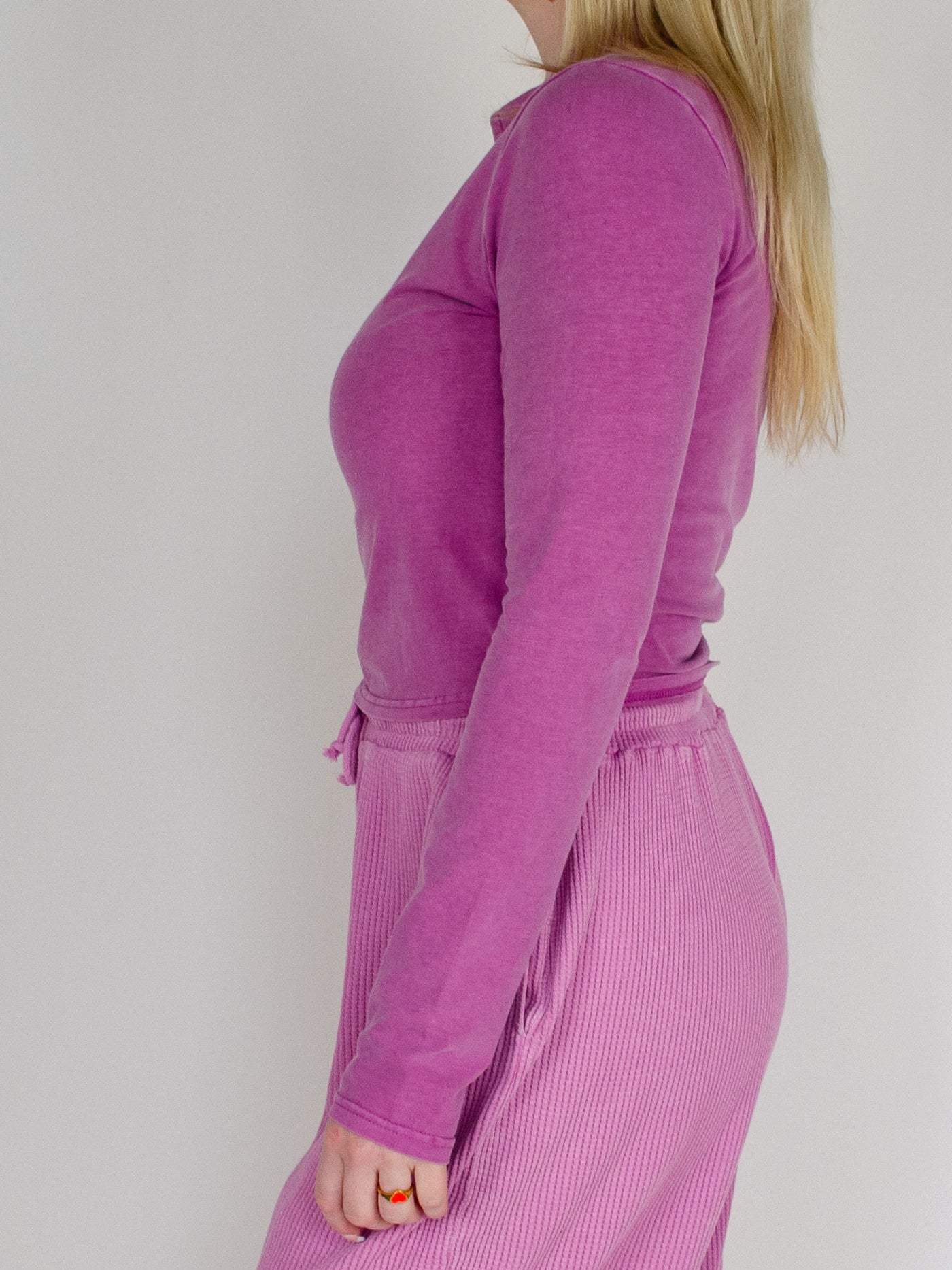 Model wearing cropped purple half zip with high waisted ribbed purple sweatpants and white tennis shoes.