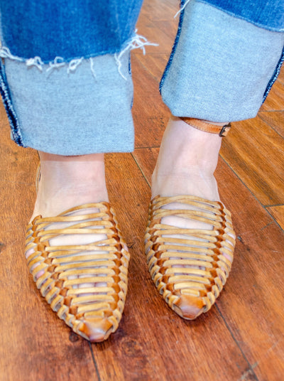 Model is wearing a tan gladiator style pointed sandal. Sandal is worn with jeans. 