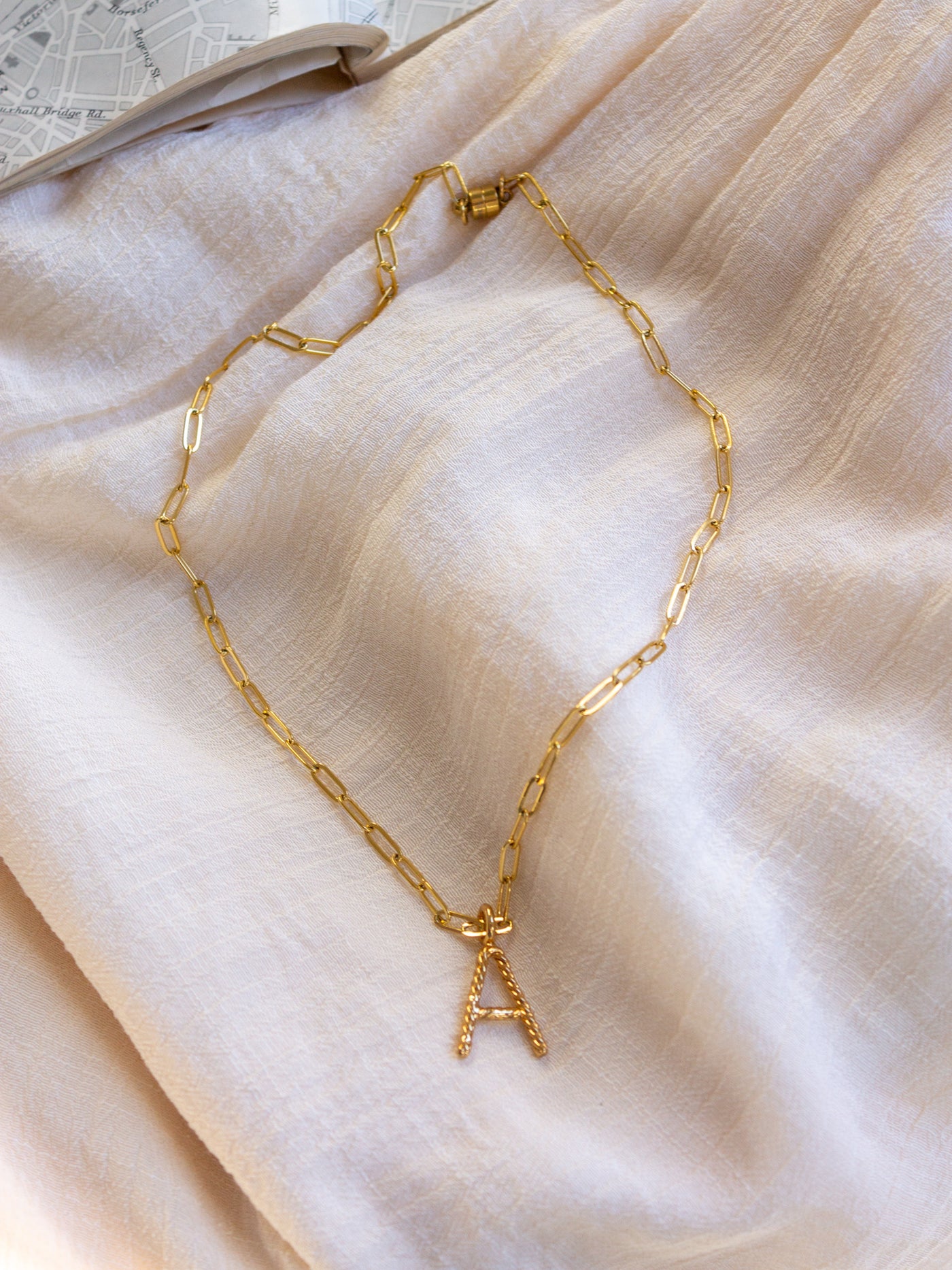 A square link/ paperclip style chain necklace with a twisted capital A attached to it.