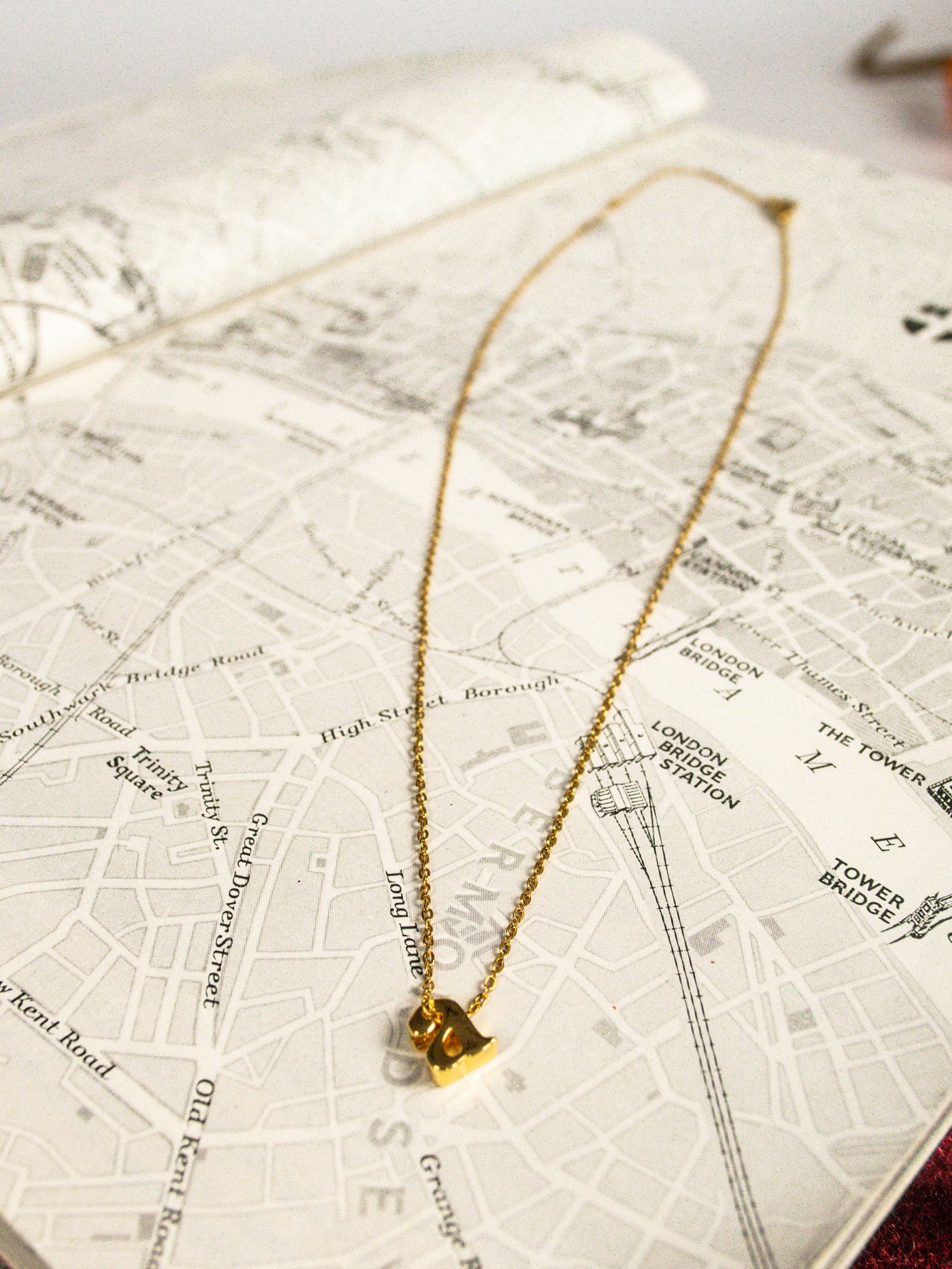 A gold mini, lowercase a initial necklace.