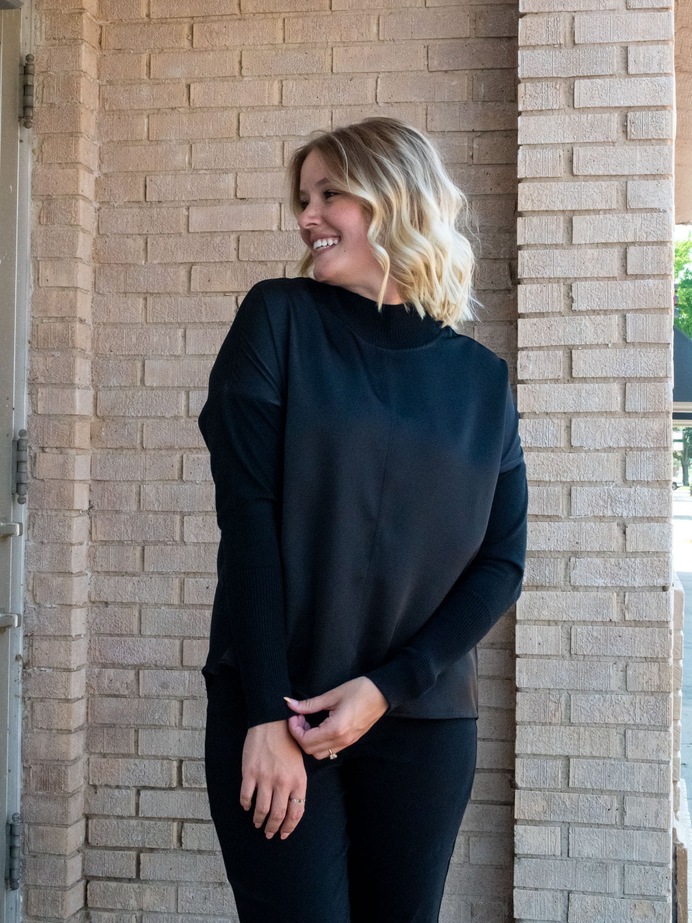 A model wearing a black top with knit sleeves. She has it paired with black pants.