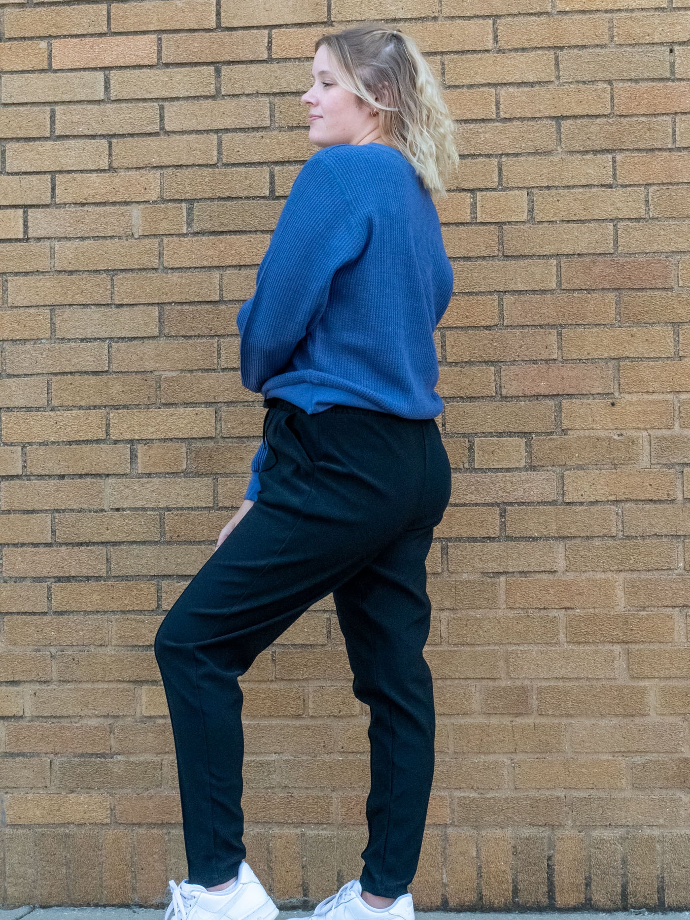 A model wearing a pair of black joggers with a seam detail. The model has it paired with a blue waffle knit top.