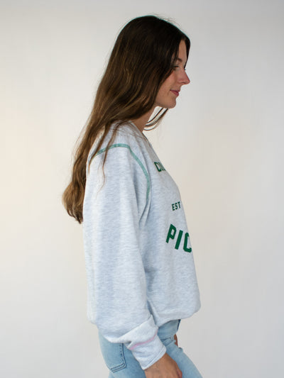 Model wearing grey heathered crewneck with green lettering that says country club and pickle ball. There is also a yellow and pink pickleball graphic!