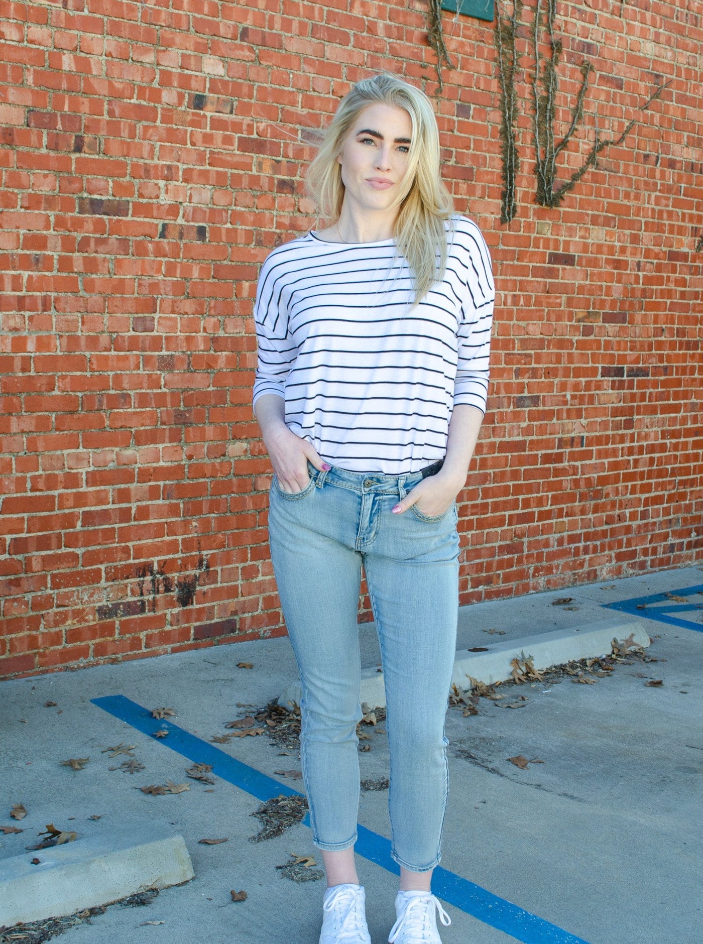 Model is wearing a low to mid rise light wash jean. Jeans are paired with a striped black and white blouse. 