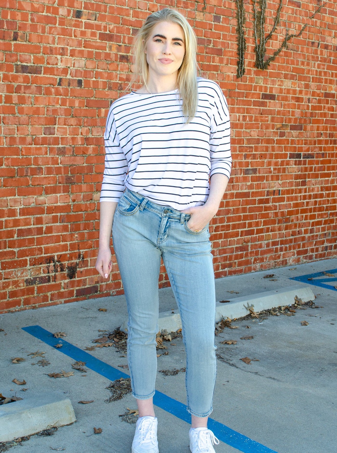 Model is wearing a low to mid rise light wash jean. Jeans are paired with a striped black and white blouse. 