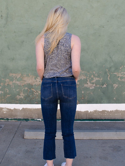 Model is wearing a dark wash 3/4th length fitted jean with a slit on each ankle. Jeans are paired with a grey tank top. 