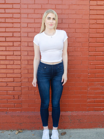 Model is wearing a dark wash skinny jean with a glide on feature that creates a easy glide on fit. Jeans are paired with a white tee.