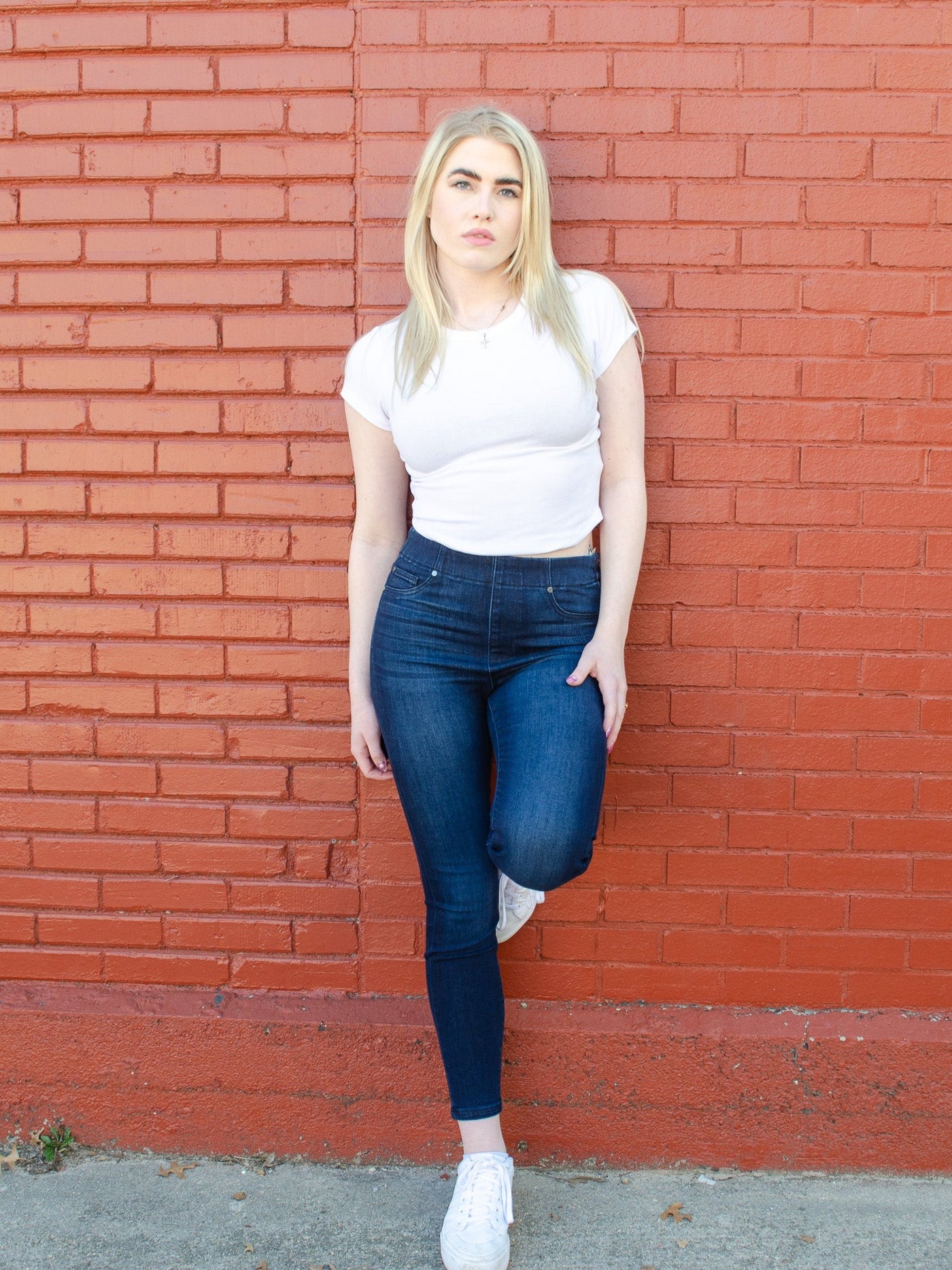 Model is wearing a dark wash skinny jean with a glide on feature that creates a easy glide on fit. Jeans are paired with a white tee