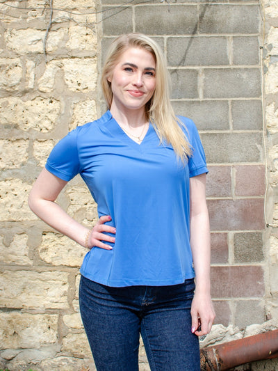 Model is wearing a blue collared athletic short sleeve t-shirt. T-shirt worn with jeans.
