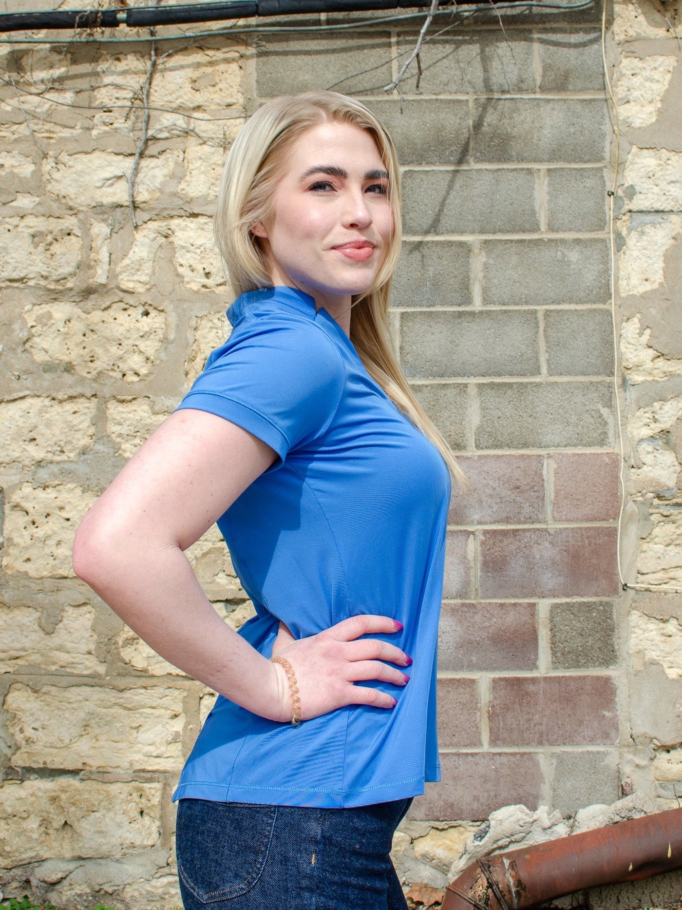 Model is wearing a blue collared athletic short sleeve t-shirt. T-shirt worn with jeans.