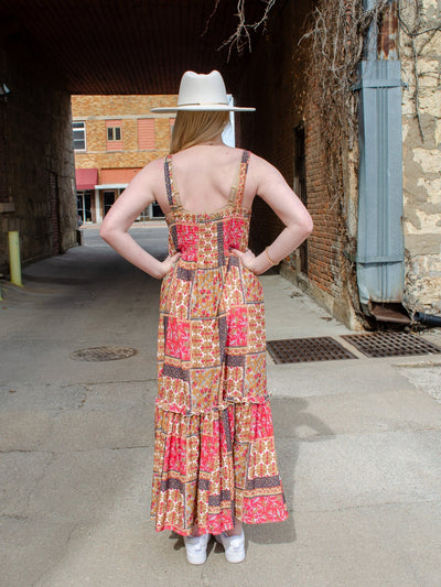 Model is wearing a multi colored patchwork print style maxi dress. Dress is paired with a flat brim hat.