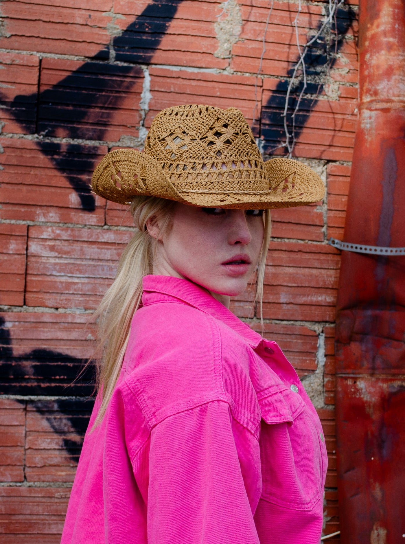 Model is wearing a straw light brown cowboy hat. 