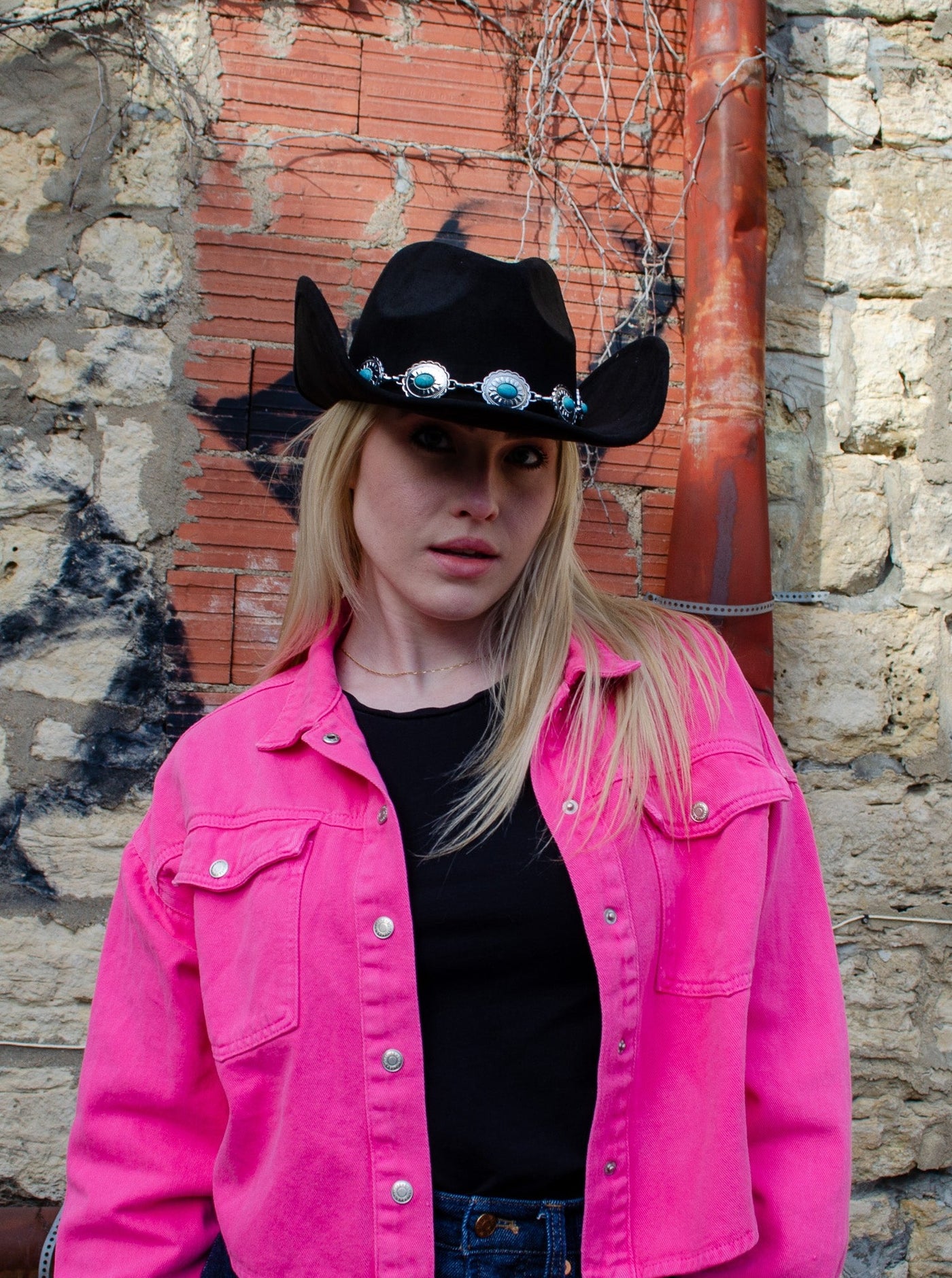 Model is wearing a black cowboy hat with turquoise and silver jewel detail. 