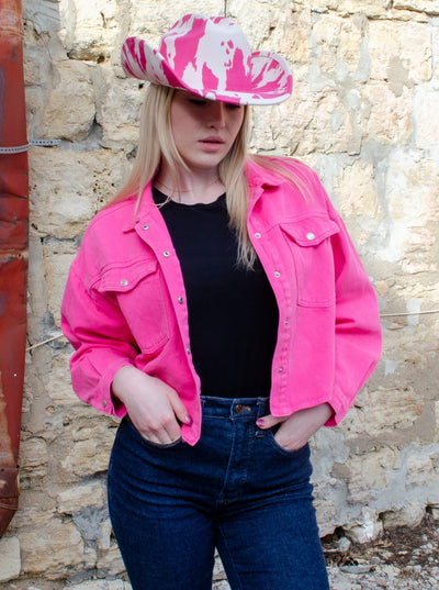 Model is wearing a pink and white cow print cowboy hat. 
