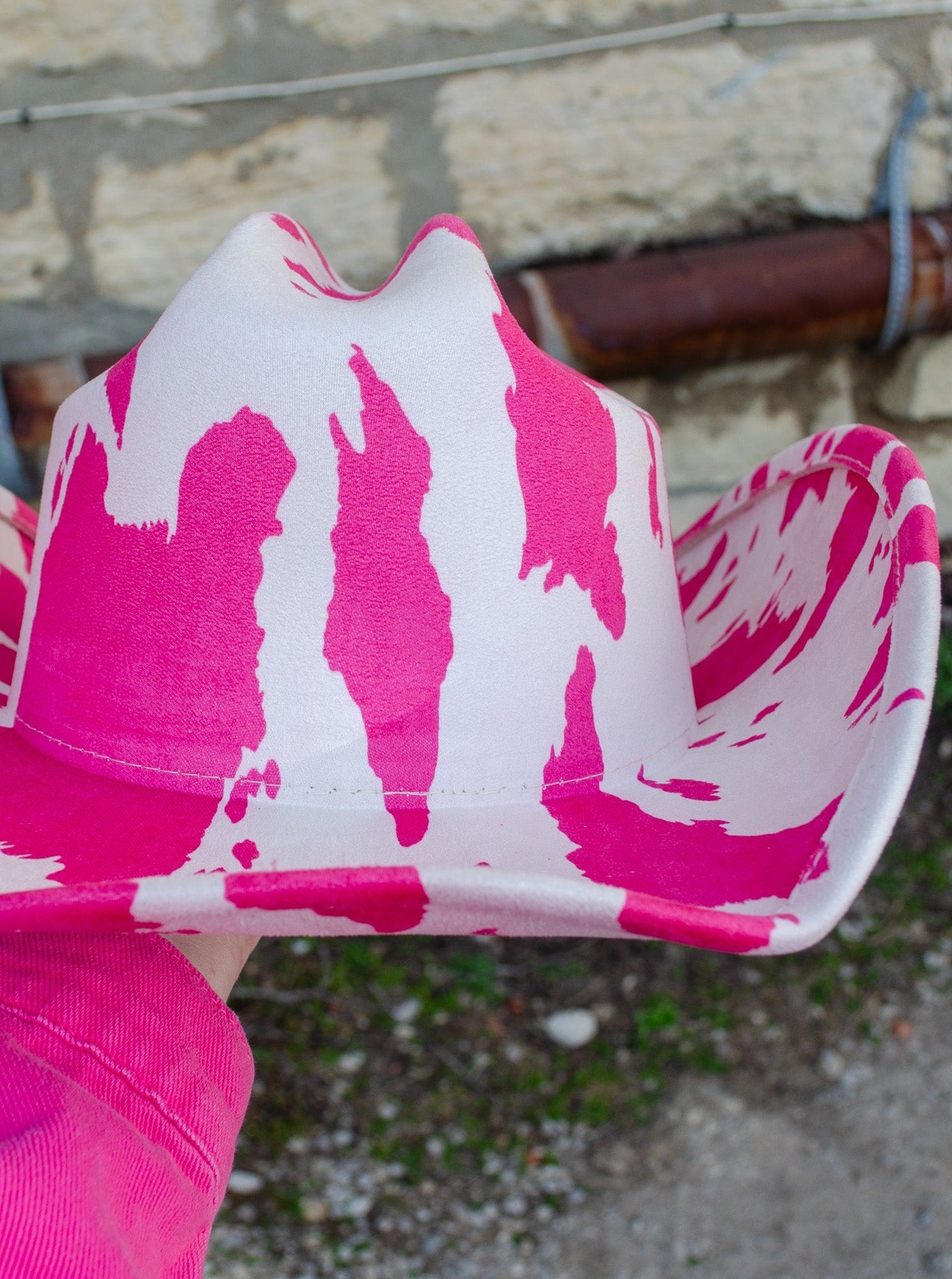 Model is wearing a pink and white cow print cowboy hat. 