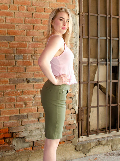 Model is wearing sage green pull on golf shorts with a tank top. 