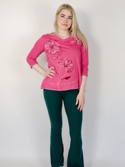 Model is wearing a rose colored V-Neck tunic top with tulips printed on the front. 