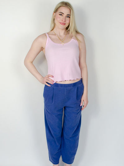 Model is wearing a low rise blue pull on sweat pant with a pink tank top.