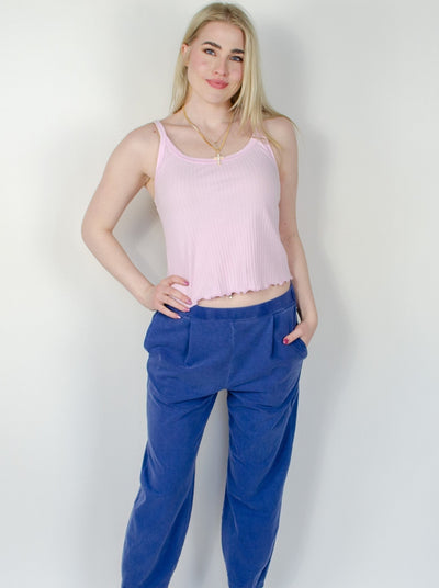 Model is wearing a low rise blue pull on sweat pant with a pink tank top
