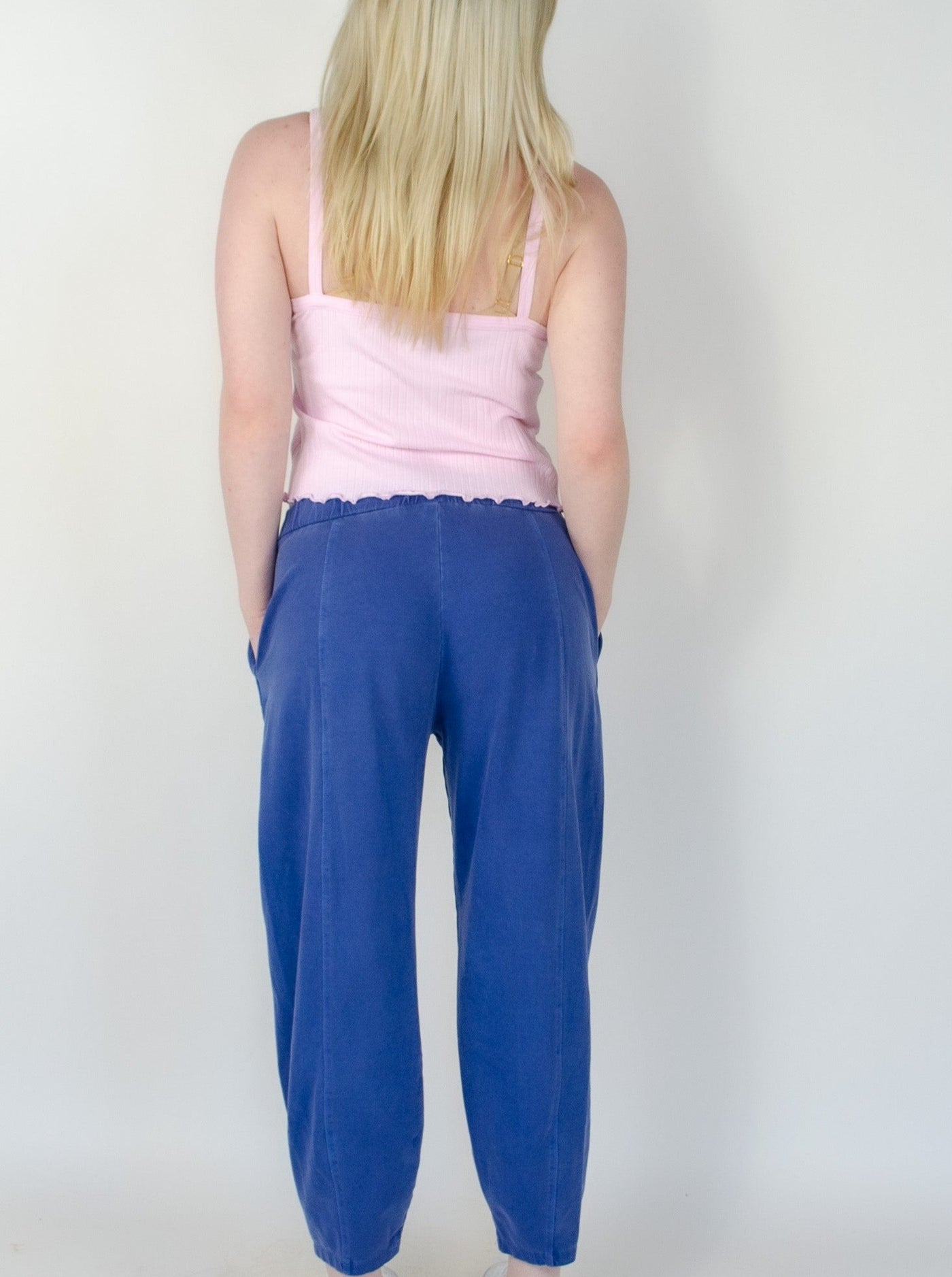 Model is wearing a low rise blue pull on sweat pant with a pink tank top