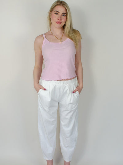 Model is wearing a low rise white pull on sweat pant with a pink tank top. 