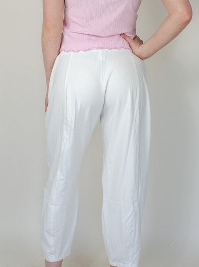 Model is wearing a low rise white pull on sweat pant with a pink tank top.