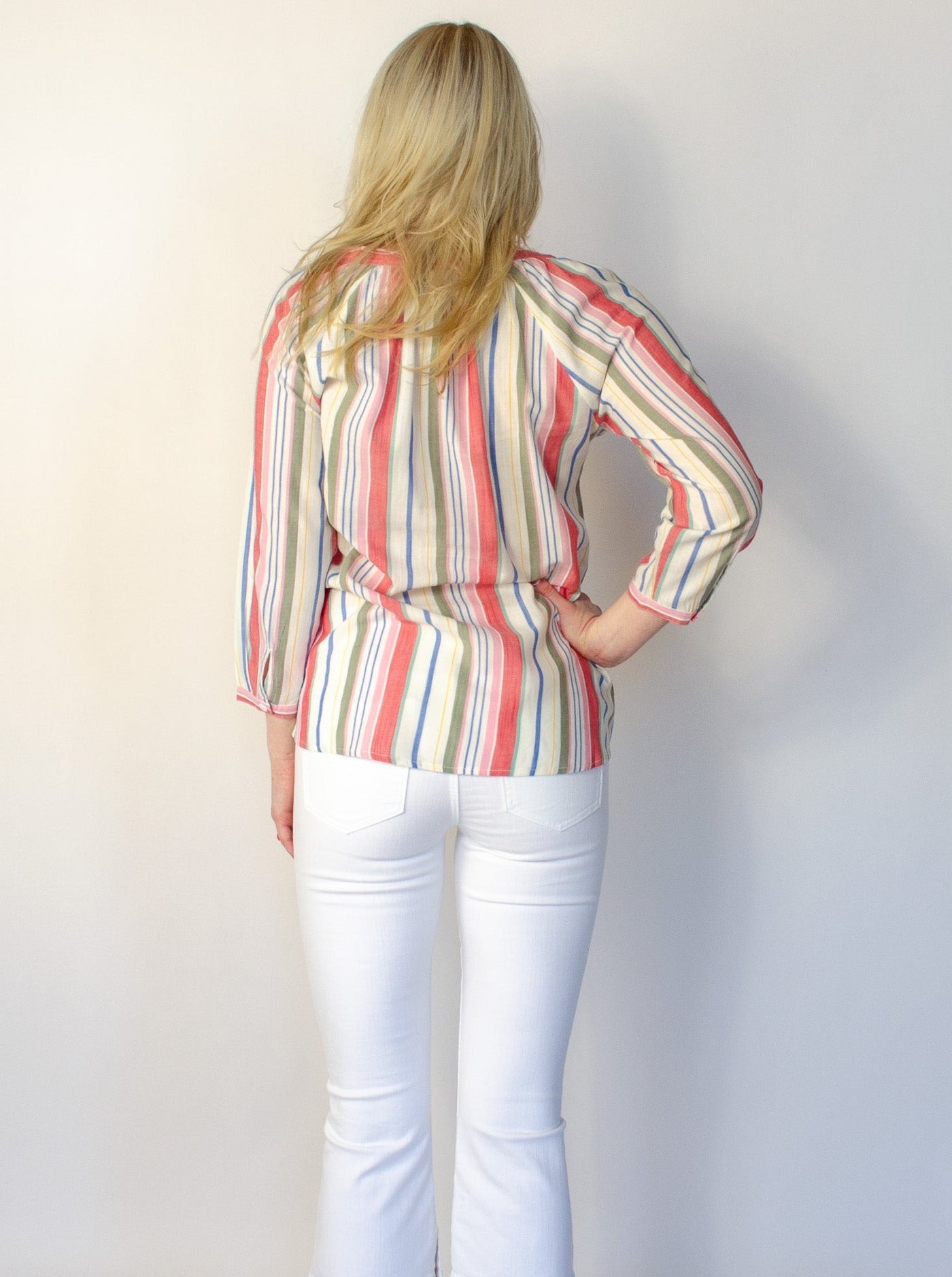 Model is wearing a vertical multi colored striped v-neck long sleeve blouse.