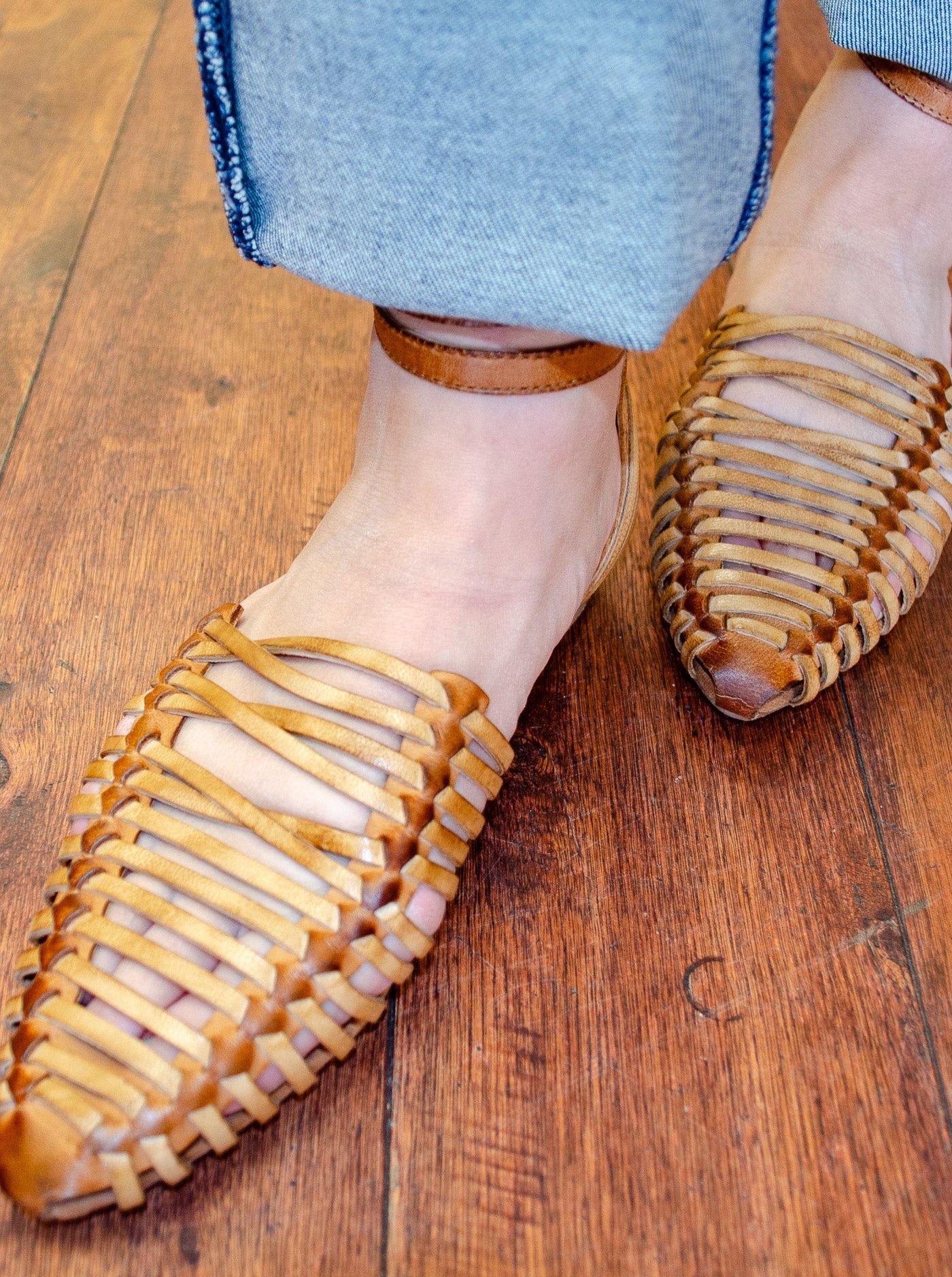 Model is wearing a tan gladiator style pointed sandal. Sandal is worn with jeans.