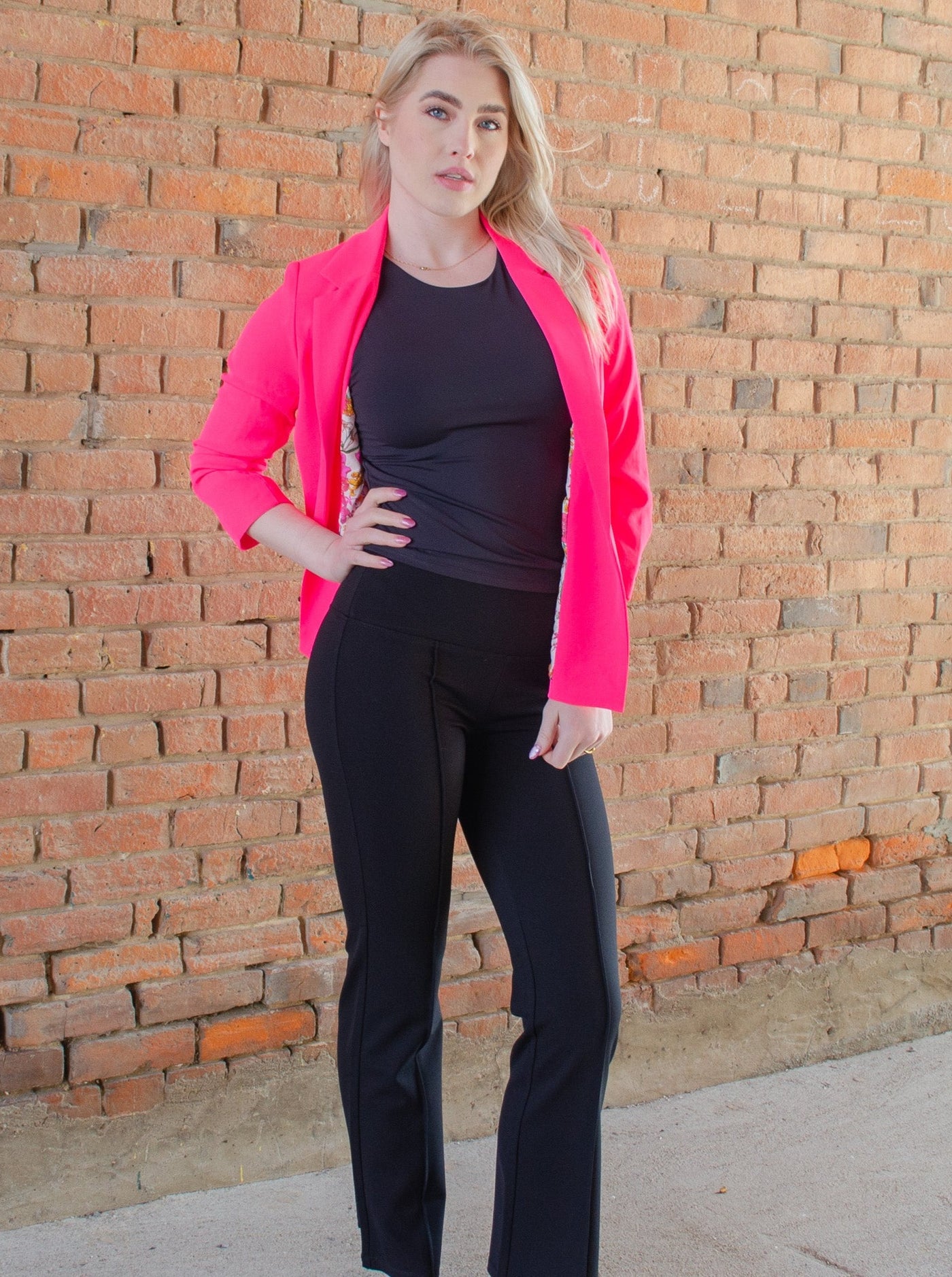 Model is wearing black flare yoga pants with a pleat down the middle of each leg. Yoga pants are paired with a black tank top. 