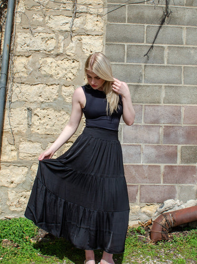 Model is wearing a black tiered maxi skirt. Maxi is paired with a black tank top. 