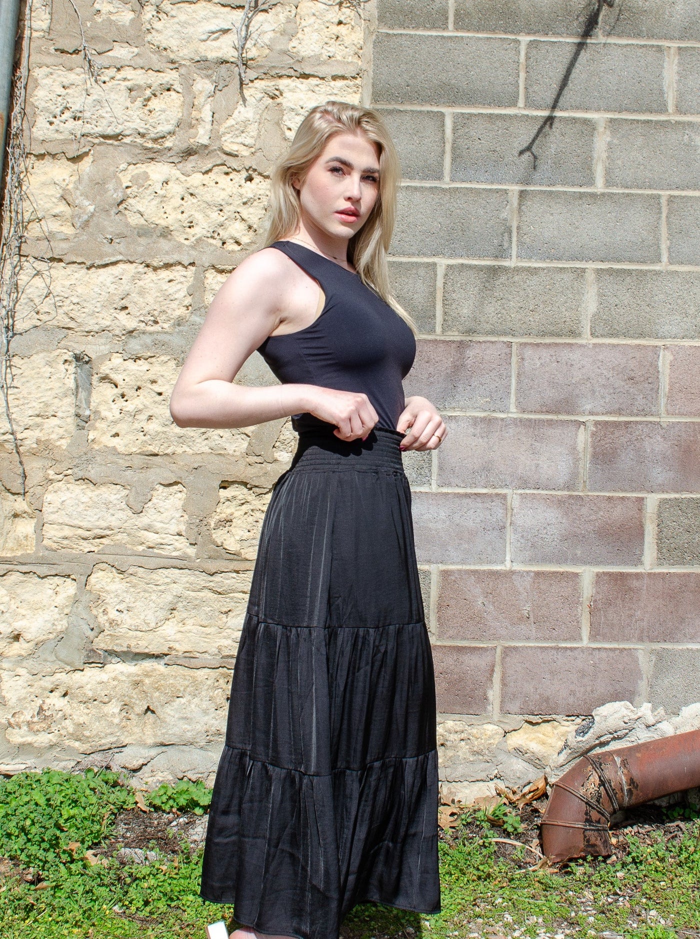 Model is wearing a black tiered maxi skirt. Maxi is paired with a black tank top. 