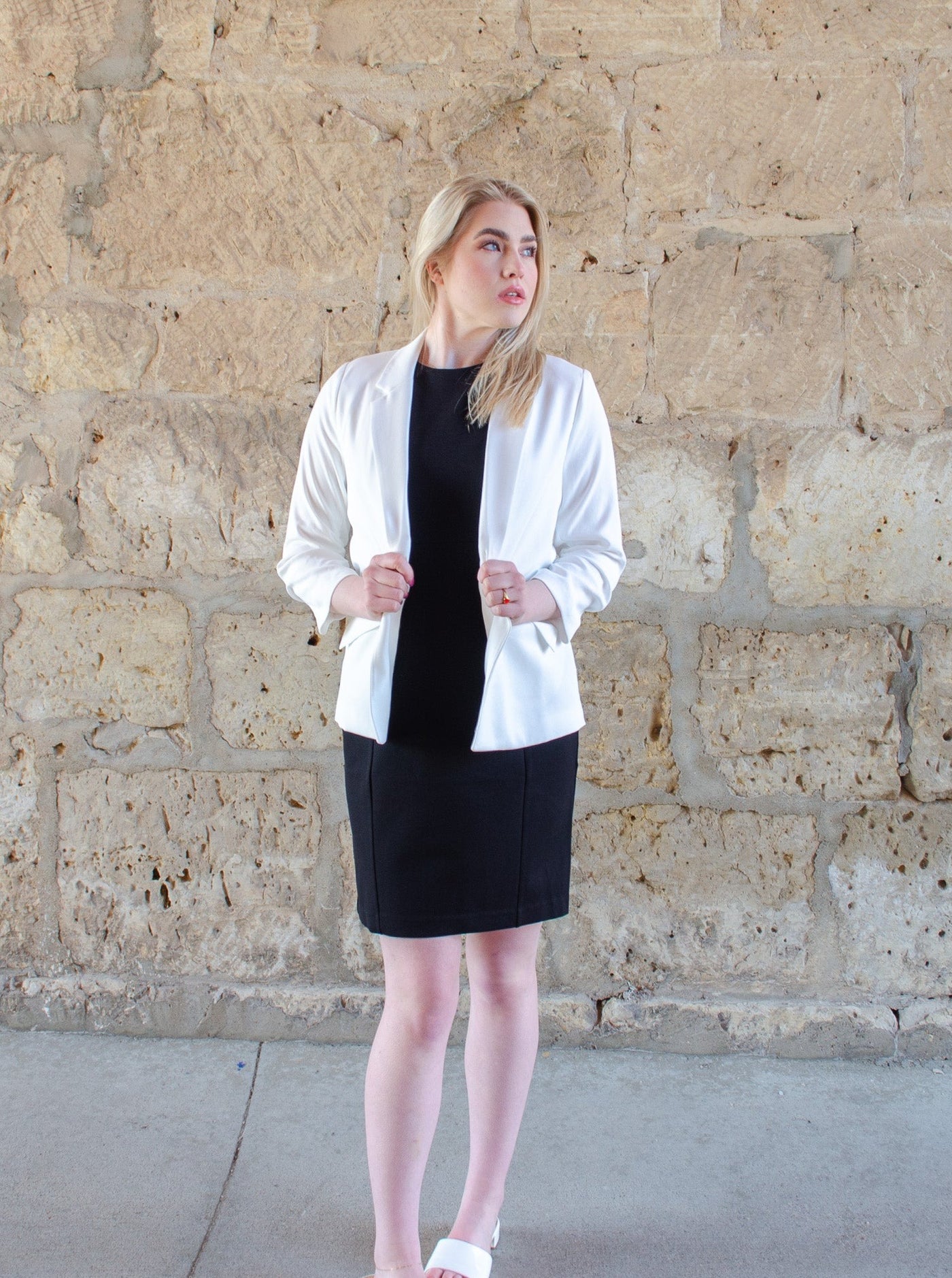 Model is wearing a black professional style midi dress. Worn with a white blazer. 