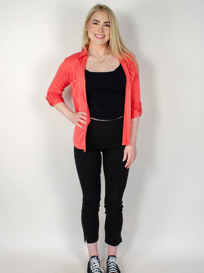 Model is wearing a black ankle pull on pant with small slits at the ankles. Pant is worn with a tank top and salmon colored button up.