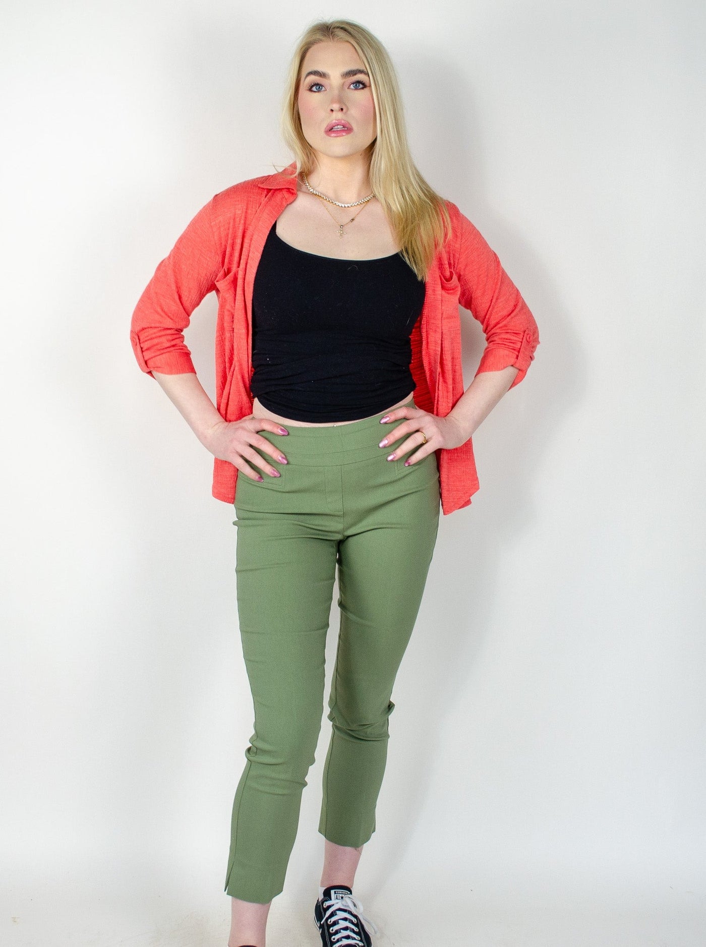 Model is wearing a sage green ankle pull on pant with small slits at the ankles. Pant is worn with a tank top and salmon colored button up.