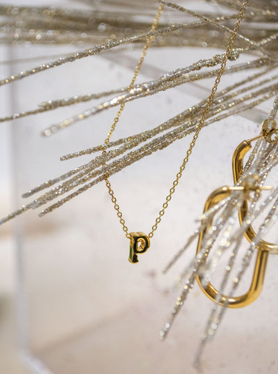 A gold necklace with a mini "p" pendant and small link chain.