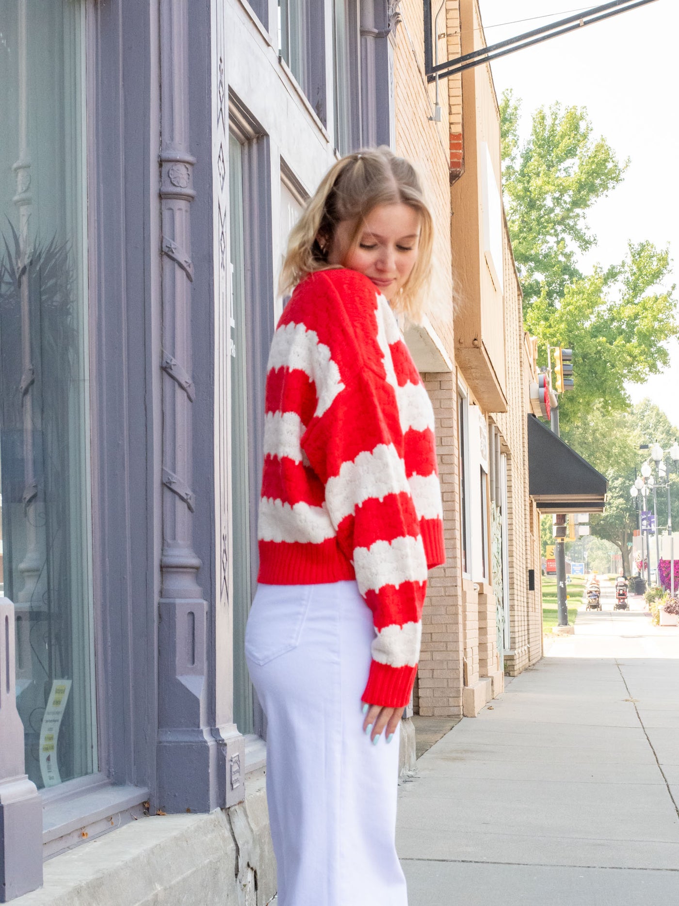 A model wearing a red and white scallop striped sweater. She has it paired with white jeans.