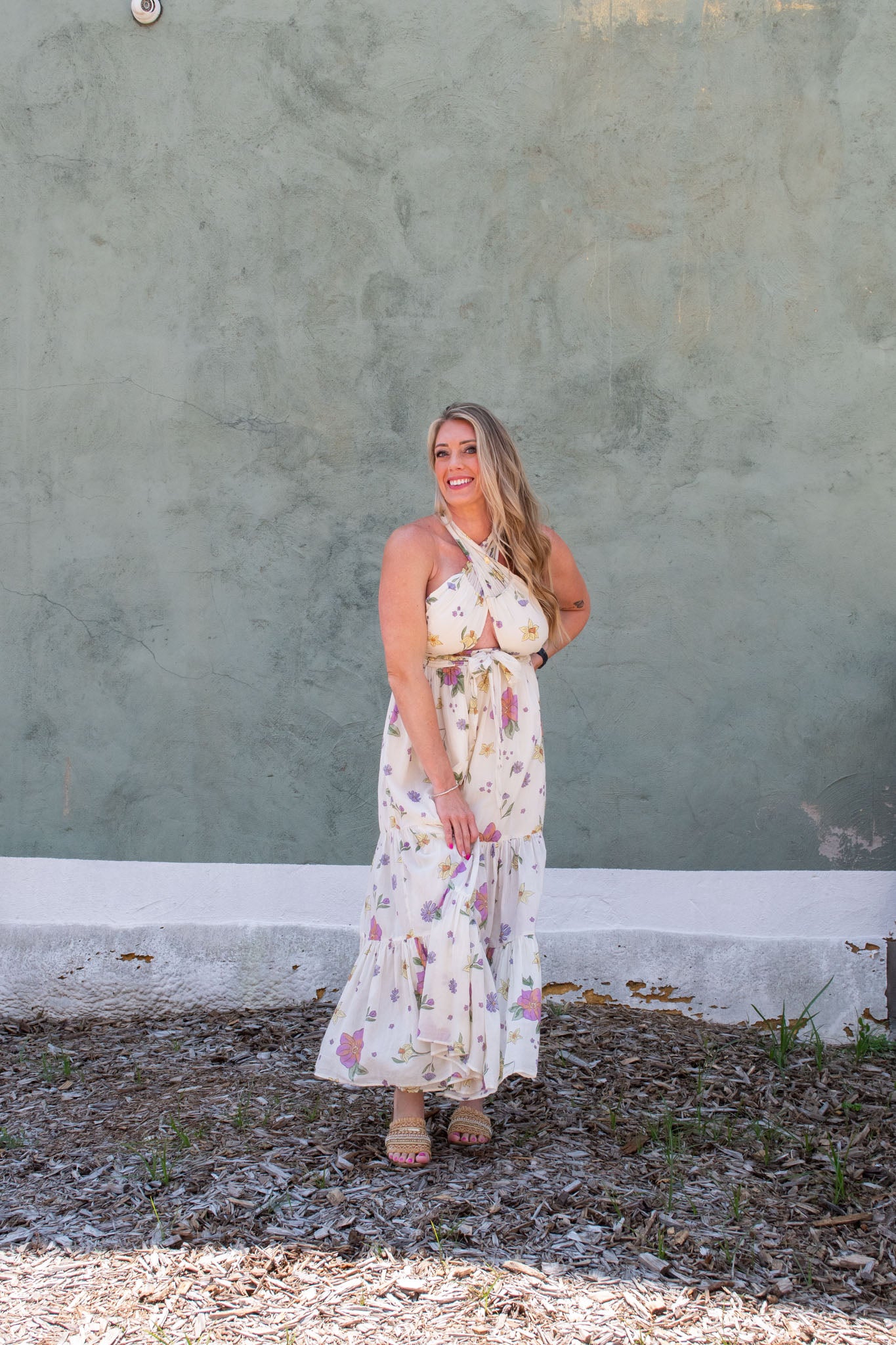 A model wearing a cream maxi skirt/dress with an allover floral print.She paired it with slip on sandals.