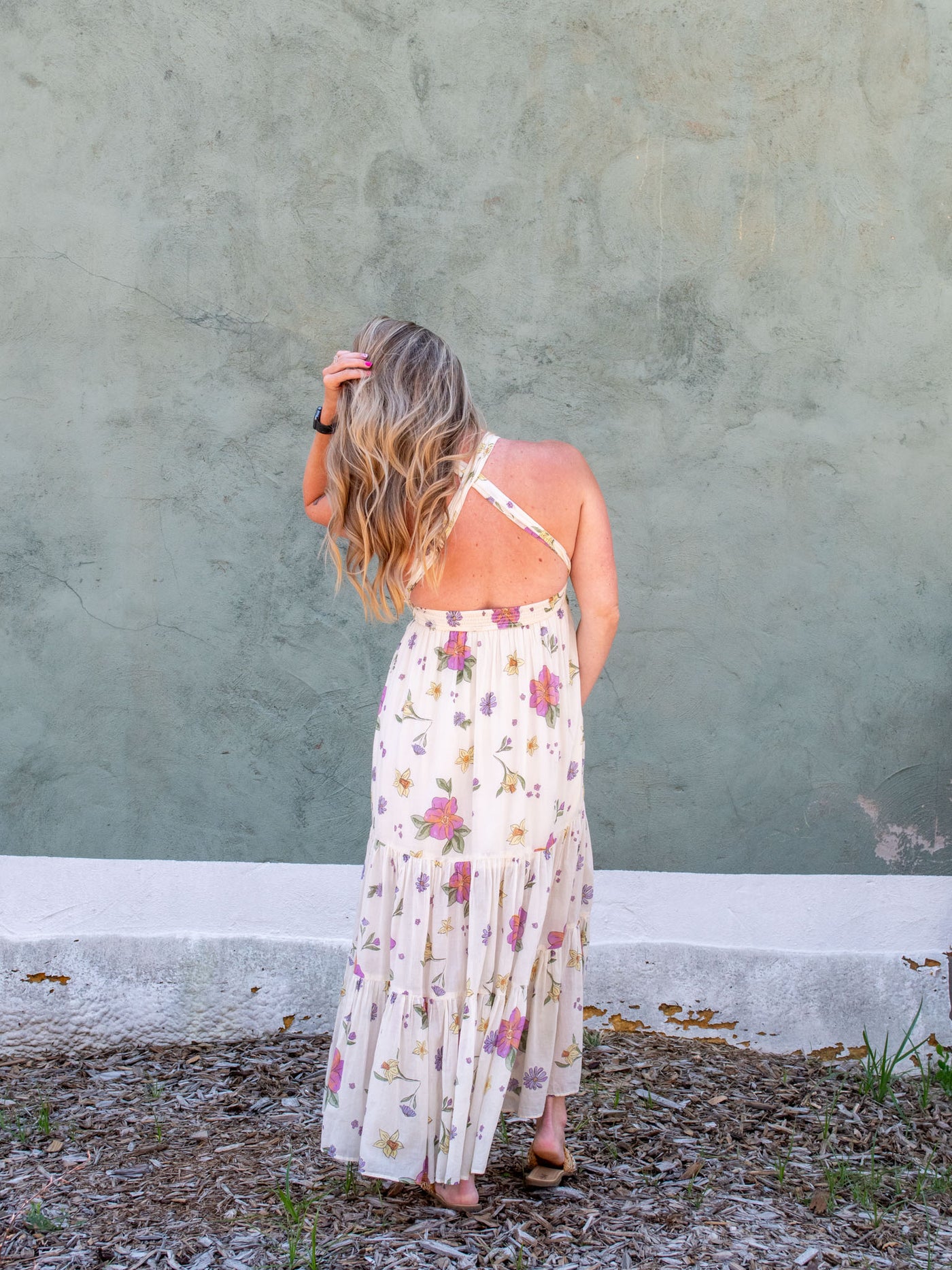 A model wearing a cream maxi skirt/dress with an allover floral print.She paired it with slip on sandals.