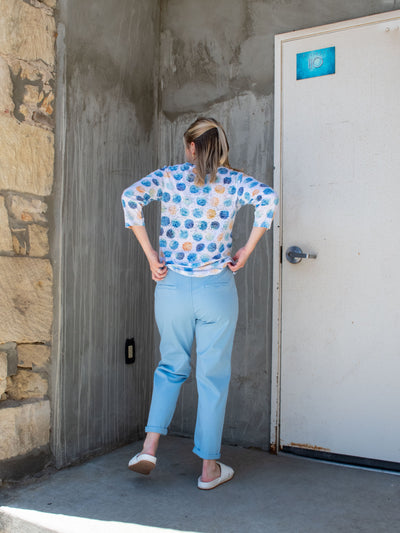 A model wearing a pair of blue faux denim joggers with a polka dot top and white slide sandals.