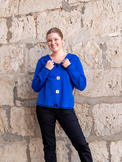 A model wearing a royal blue button up sweater with a hood. The model has it paired with a black rhinestone jean.