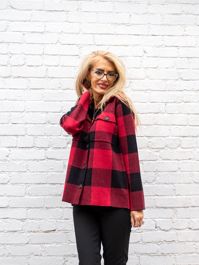A model wearing a buffalo red and black plaid button up sweater. The model has it paired with a black skinny jean.
