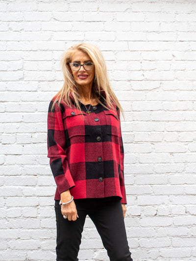 A model wearing a buffalo red and black plaid button up sweater. The model has it paired with a black skinny jean.