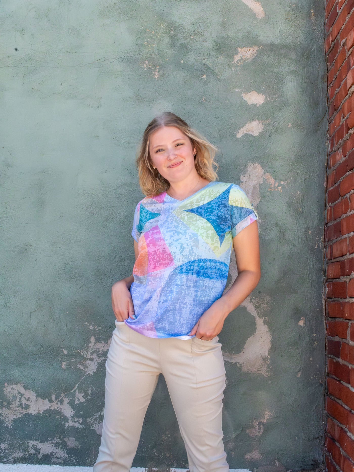 A model wearing a colorful v-neck top with a tile printed pattern. The model paired it with a pair of khaki pants.