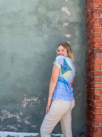 A model wearing a colorful v-neck top with a tile printed pattern. The model paired it with a pair of khaki pants.
