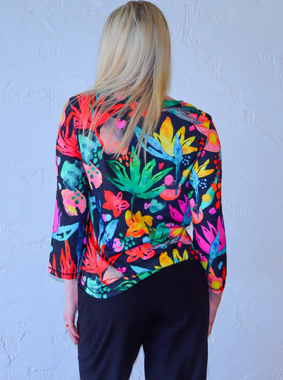 Model is wearing a quarter sleeve multi colored neon and black floral printed shirt paired with high waisted black joggers.
