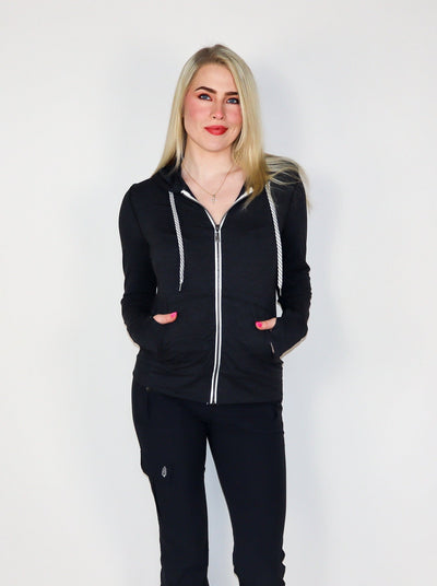 Model is wearing a deep charcoal colored fitted zip up with white trimming and white drawstrings. 