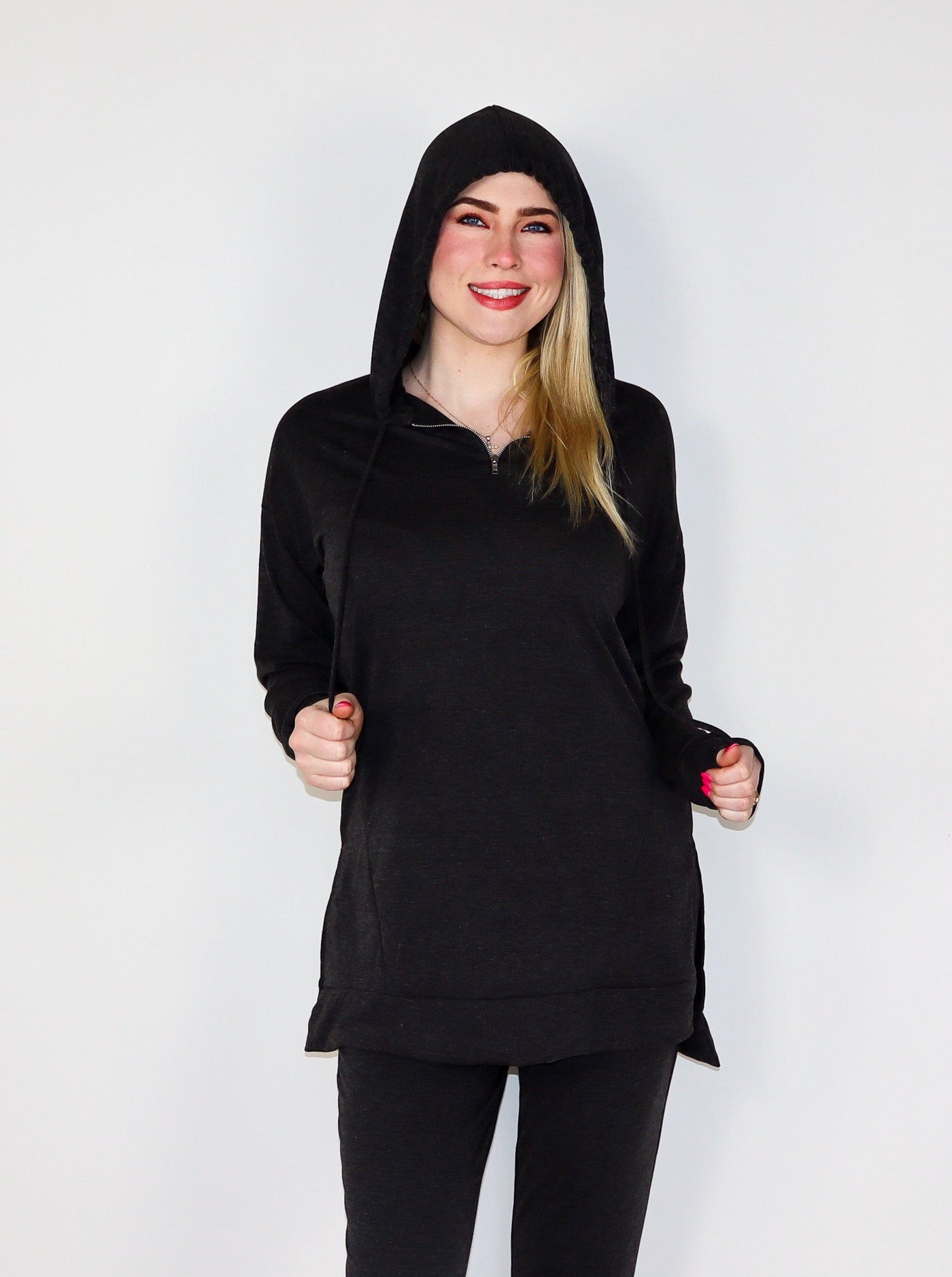 Model is wearing a deep charcoal colored oversized hooded quarter zip paired with matching joggers.