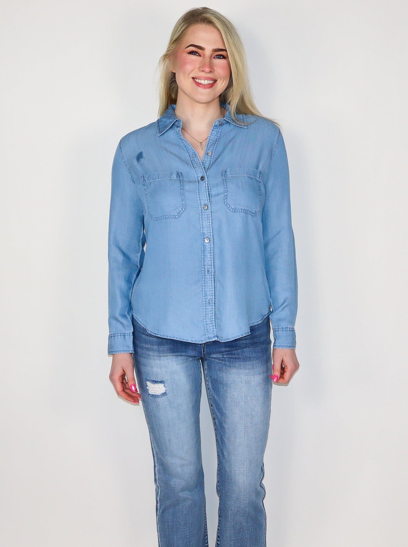 Model is wearing a light wash blue denim button up. Button up is paired with blue jeans. 