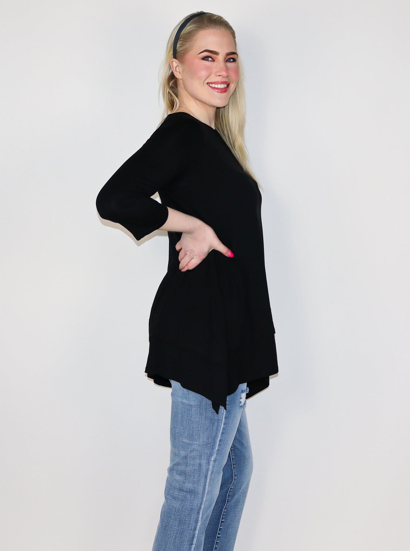 The model is wearing a flowey 3/4th length sleeve black fitted longsleeve. Top is paired with jeans.