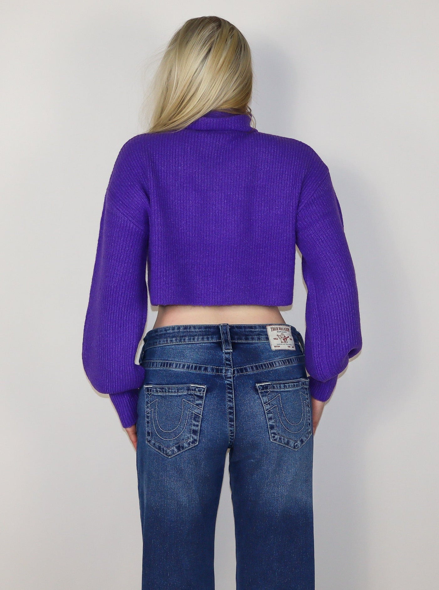 Model is wearing a deep purple cropped turtle neck. Worn with jeans. 